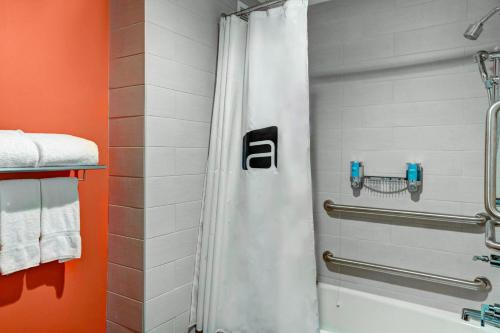 a bathroom with a shower with a white shower curtain at Aloft Raleigh Durham Airport Brier Creek in Raleigh
