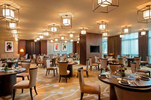 a restaurant with tables and chairs and a flat screen tv at Sheraton Bailuhu Resort, Huizhou in Huizhou