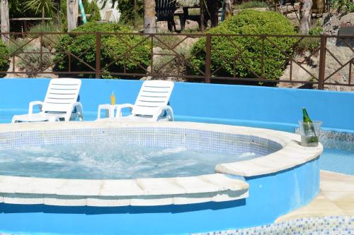a pool with two chairs and a bottle of wine at Complejo Los Cipreses in Villa Carlos Paz