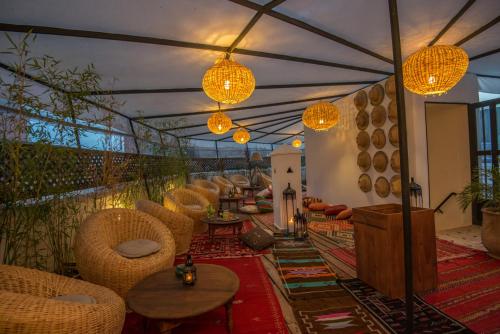 d'une terrasse avec des chaises, des tables et des lumières. dans l'établissement Hotel & Spa Riad El Walaa, à Marrakech