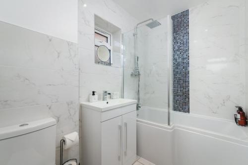 uma casa de banho branca com um lavatório e um chuveiro em Arete Serviced Accommodation - 3 Bedrooms, 4 Beds, with Parking em Merstham