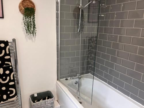 ein Bad mit einer Badewanne und einer Dusche mit grauen Fliesen in der Unterkunft Sunderland Stays, Romford, Luxury House - City Centre & Hospital in Sunderland