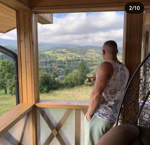 a man standing on a balcony looking out of a window at Байка Карпат in Vorokhta