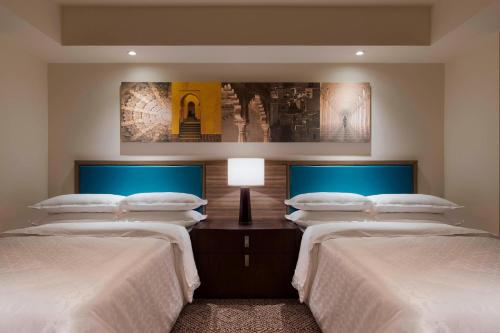 a bedroom with two beds and a table with a lamp at Sheraton Hyderabad Hotel in Hyderabad