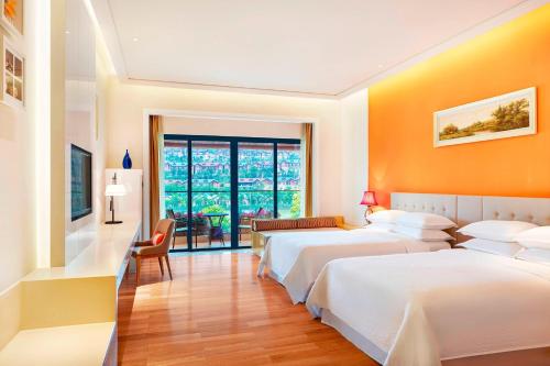 two beds in a room with orange walls at Four Points by Sheraton Heyuan Resort in Heyuan
