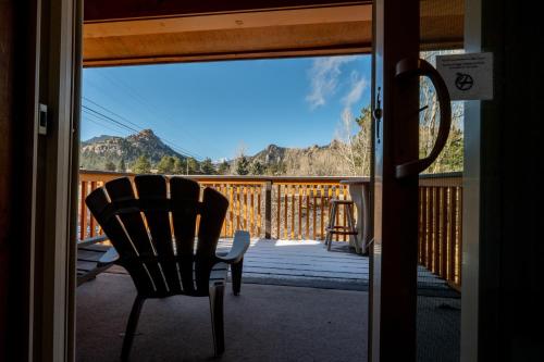 a door open to a porch with a chair and mountains at Murphy's River Lodge in Estes Park