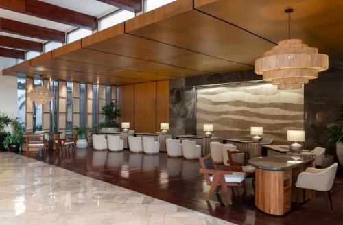 un hall avec des chaises et des tables blanches dans un bâtiment dans l'établissement Fairmont Mayakoba, à Playa del Carmen