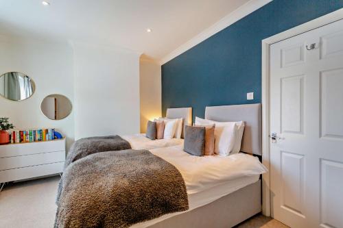 a bedroom with two beds and a blue wall at 3-bedroom home with free parking&flexible bed configuration in Harrogate