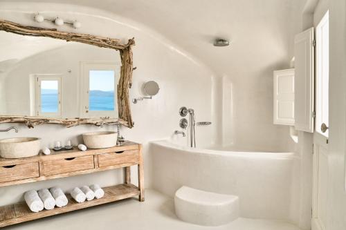a bathroom with a tub and a sink and a mirror at Mystique, a Luxury Collection Hotel, Santorini in Oia