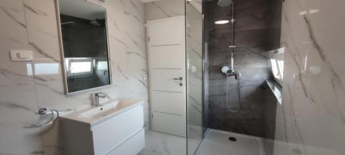 a bathroom with a shower and a sink and a mirror at Apartments INBOX in Kostrena