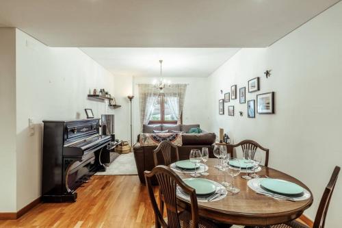 a dining room with a table and a piano at Charmoso Apartamento Sacavém in Sacavém