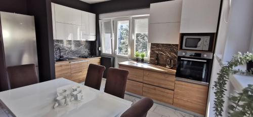 - une cuisine avec une table et des chaises blanches ainsi qu'une cuisinière dans l'établissement Apartman Wolf, à Varaždin
