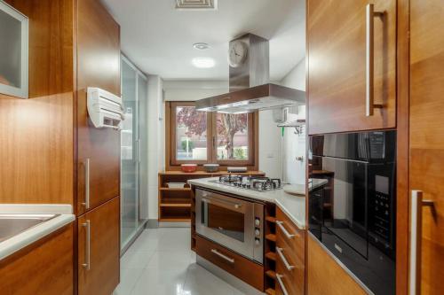a kitchen with stainless steel appliances and wooden cabinets at Charmoso Apartamento Sacavém in Sacavém
