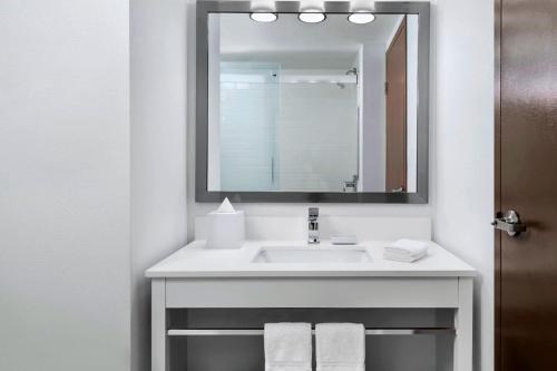 a bathroom with a sink with a mirror and towels at Four Points by Sheraton Barrie in Barrie