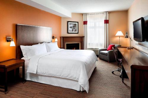 um quarto de hotel com uma grande cama branca e uma cadeira em Four Points by Sheraton Barrie em Barrie