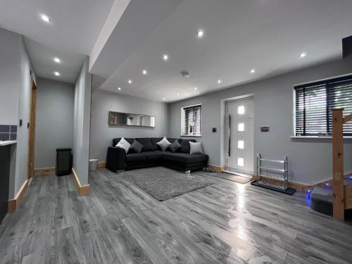 a living room with a black couch and a fireplace at Entire Two Bedroom Guest House & Free Parking in Nottingham