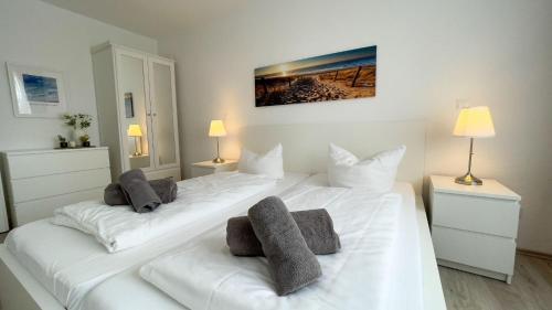 2 weiße Betten in einem Zimmer mit 2 Lampen in der Unterkunft Strandhaus Nordseebrandung Fewo B4.1 in Cuxhaven