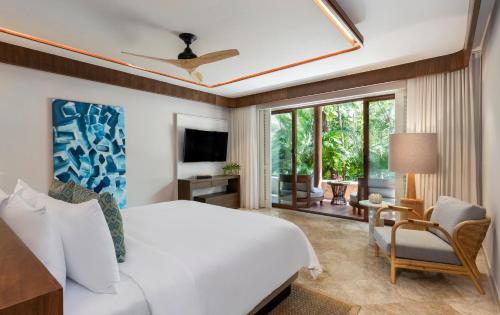 a bedroom with a large white bed and a tv at Fairmont Mayakoba in Playa del Carmen