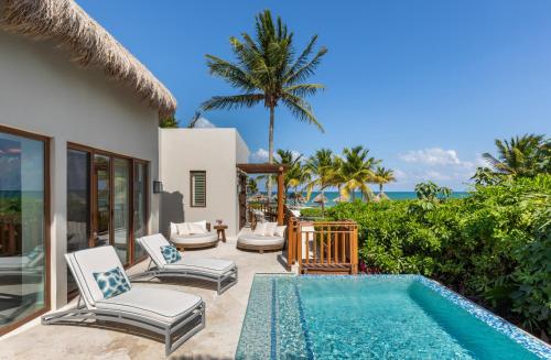 a villa with a swimming pool next to a house at Fairmont Mayakoba in Playa del Carmen