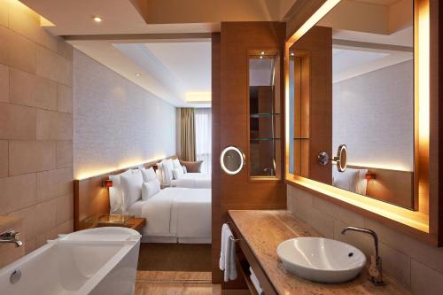 a bathroom with a bed and a sink and a tub at The Westin Mumbai Garden City in Mumbai