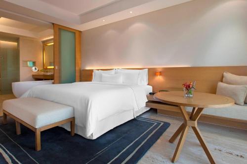 um quarto de hotel com uma cama grande e uma mesa em The Westin Mumbai Garden City em Mumbai