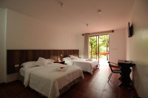 a hotel room with two beds and a window at Lava House Hostal in Puerto Ayora