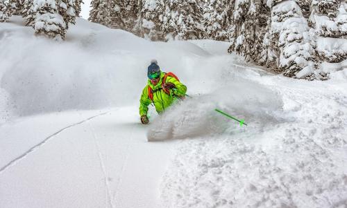 a man is skiing down a snow covered slope at Eleven Revelstoke Lodge in Revelstoke