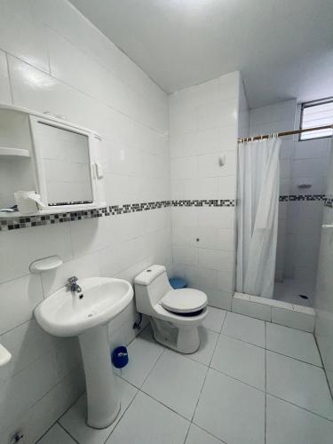 a white bathroom with a toilet and a sink at Departamento hermoso frente a chipipe in Salinas