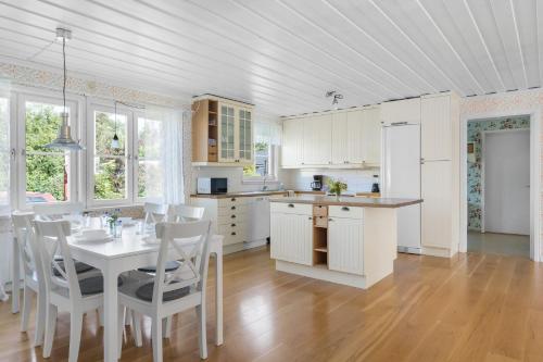 a kitchen with a table and white cabinets and a table and chairs at Scenic Seaside Retreat near Northvolt Ett in Skellefteå