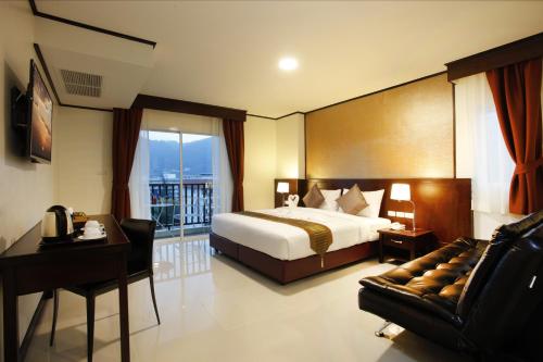 1 dormitorio con cama, escritorio y sofá en Orchid Resortel, en Patong Beach