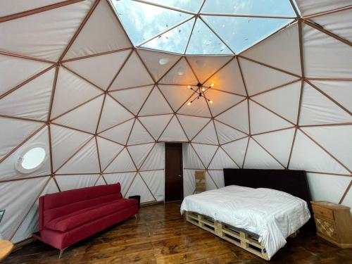 Cette chambre comprend une tente avec un lit et un canapé rouge. dans l'établissement MANDALA CAMP, à Tomatlán