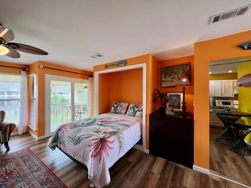 a bedroom with orange walls and a bed and a kitchen at Sandpiper Cove 8224 in Destin