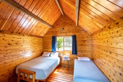 a room with two beds in a wooden cabin at Redwood Coast Cabins and RV Resort in Eureka