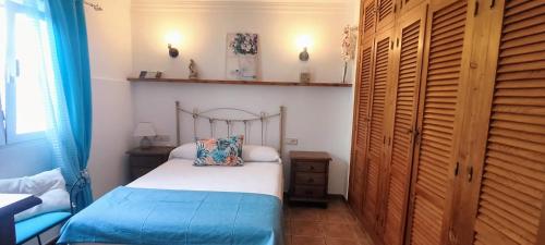 een kleine slaapkamer met een bed met een houten hoofdeinde bij Estudio Patio San Paulino II in Barbate