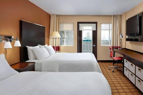 a hotel room with two beds and a television at Four Points by Sheraton Hotel & Suites Calgary West in Calgary