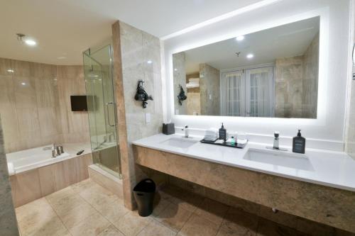 a bathroom with two sinks and a shower and a mirror at Sheraton Laval Hotel in Laval