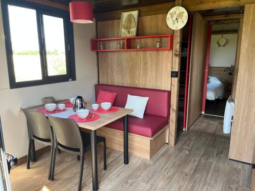 a dining room with a table and a red bench at DOMAINE DES GALINACES ROULOTTE LA ROUSSETTE 2-4P in Marigny-lès-Reullée