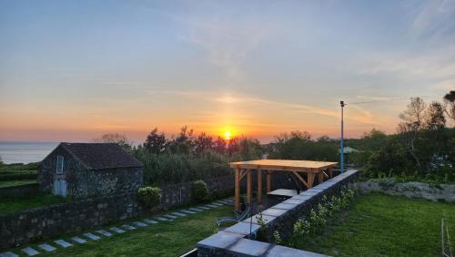 a picnic table in a yard with a sunset in the background at Casas de Campo Lomba D' Água - Turismo Rural in Candelária