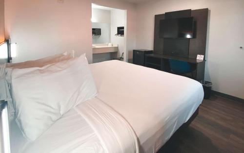 a hotel room with a white bed and a tv at Motel 6-West Sacramento, CA in West Sacramento