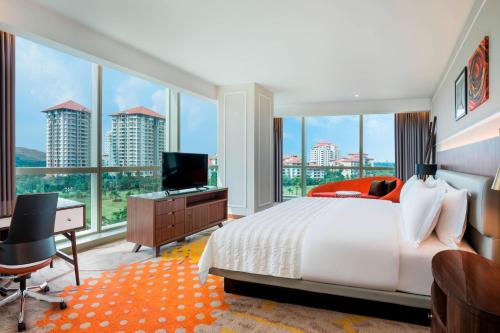 a bedroom with a bed and a desk with a television at Le Meridien Putrajaya in Putrajaya