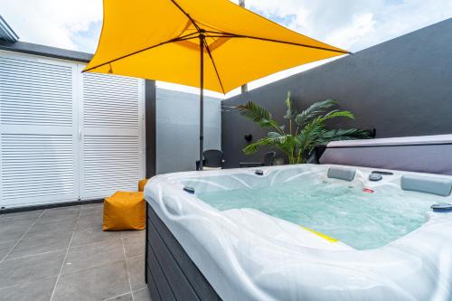 a hot tub with an umbrella on a patio at Foral Dreams in Fajã de Cima