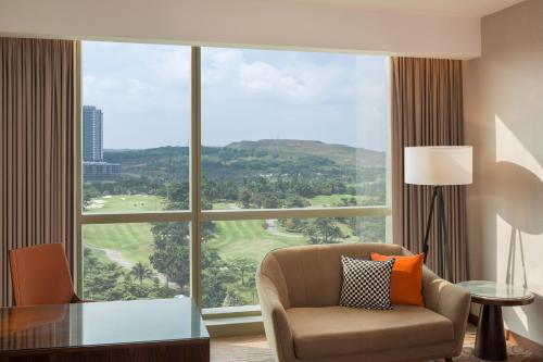 a living room with a chair and a large window at Le Meridien Putrajaya in Putrajaya