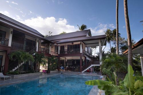 a house with a swimming pool in front of it at Coconut Tree Homestay in Ban Wa Thon
