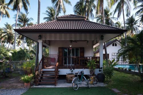 una casa con una bicicleta estacionada frente a ella en Coconut Tree Homestay, en Ban Wa Thon