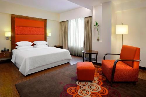 Habitación de hotel con cama y silla en Four Points by Sheraton Ahmedabad en Ahmedabad