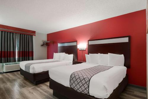 two beds in a hotel room with red walls at SureStay Plus Hotel by Best Western San Antonio North in San Antonio