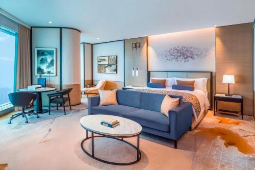 a hotel room with a bed and a blue couch at Meixi Lake Hotel, a Luxury Collection Hotel, Changsha in Changsha