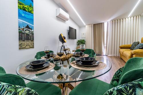 a living room with a glass table and green chairs at Foral Dreams in Fajã de Cima