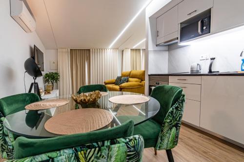 a living room with a table and green chairs at Foral Dreams in Fajã de Cima