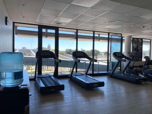 a gym with several treadmills in a room with windows at Radisson Hotel & Convention Centre Johannesburg, O.R. Tambo in Johannesburg